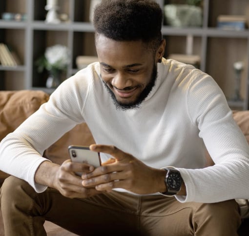 A man texting on his mobile phone in his sitting room